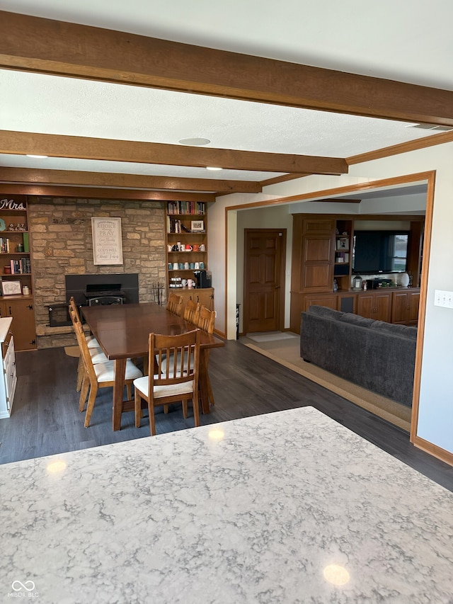 dining area featuring wood finished floors, beamed ceiling, and a fireplace