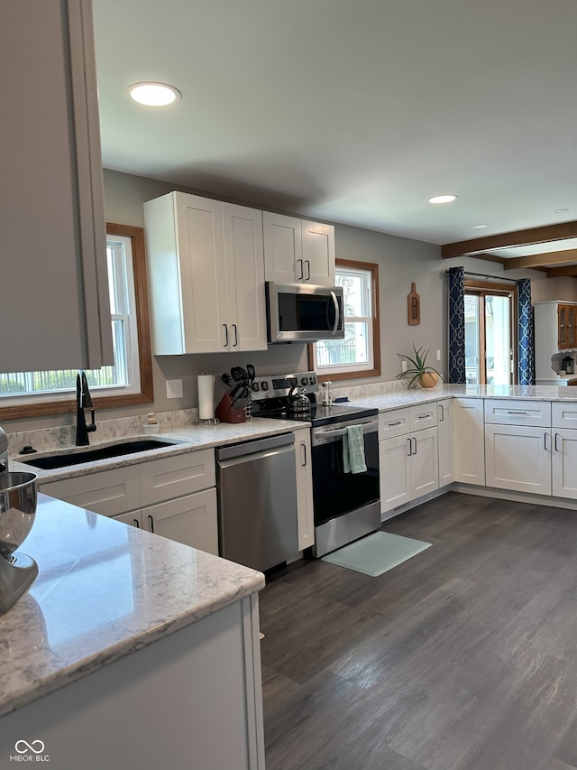 kitchen with stainless steel appliances, white cabinets, a sink, and dark wood-style floors