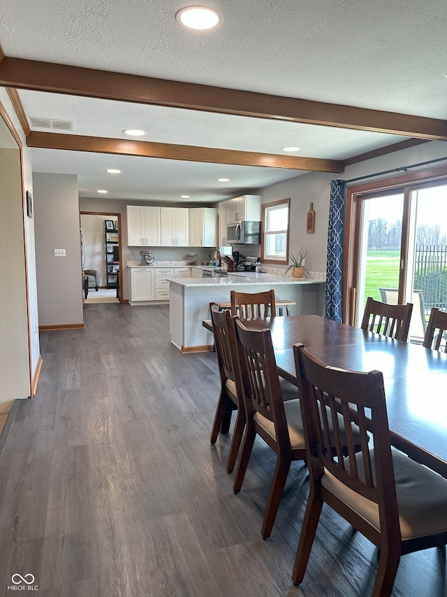 dining room featuring dark wood-type flooring, beam ceiling, and recessed lighting