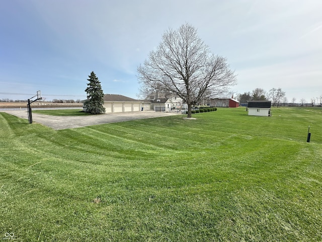 view of yard with a garage, driveway, and an outdoor structure