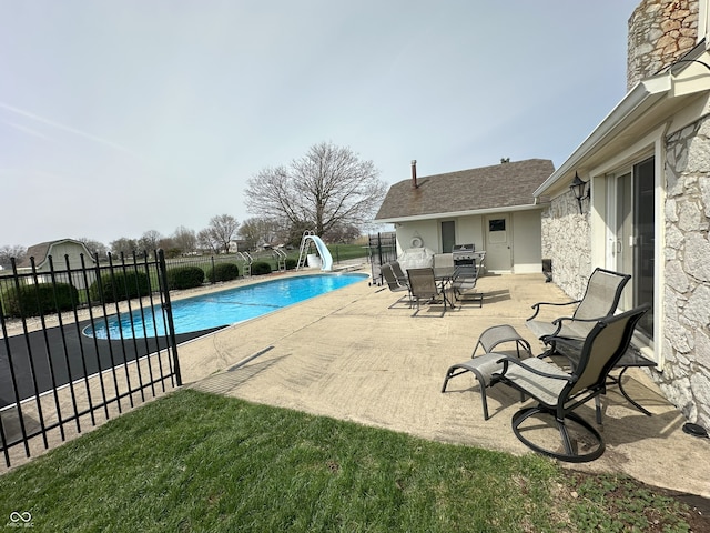 view of pool with a patio area, fence, a water slide, and a fenced in pool