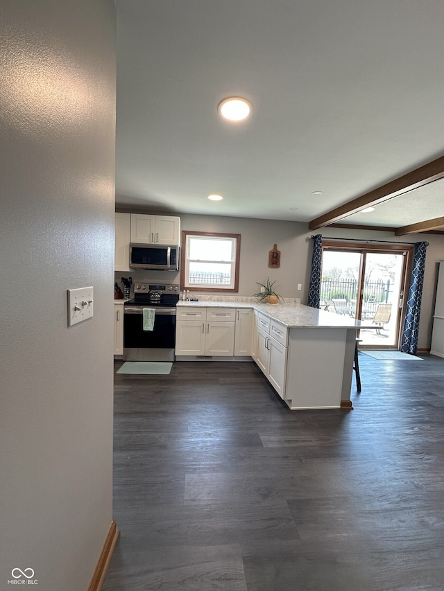 kitchen with white cabinetry, dark wood-style floors, a peninsula, and stainless steel appliances