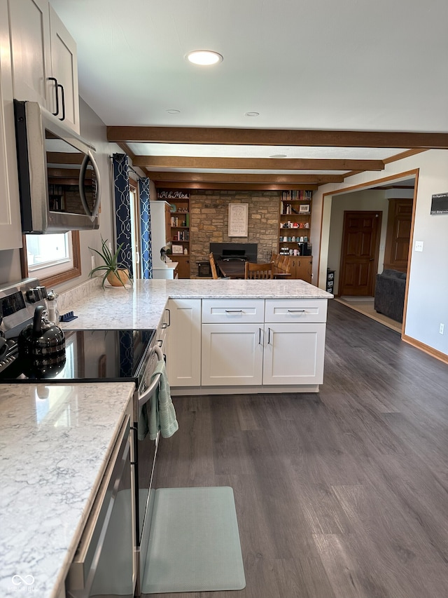 kitchen with light stone countertops, a peninsula, white cabinetry, appliances with stainless steel finishes, and dark wood-style floors