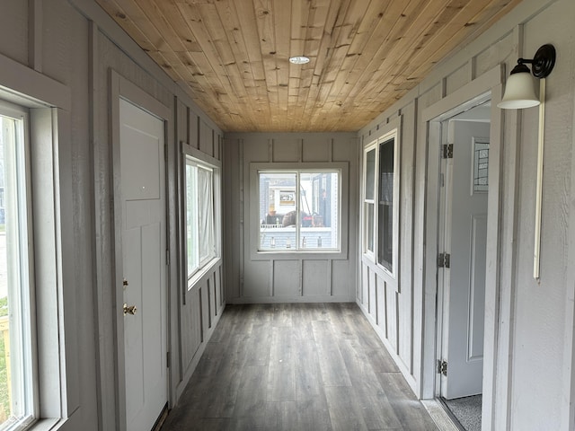 unfurnished sunroom featuring wood ceiling, wood finished floors, and a decorative wall