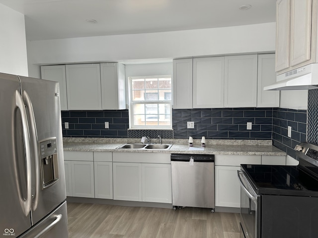 kitchen with light wood-type flooring, light countertops, under cabinet range hood, stainless steel appliances, and a sink
