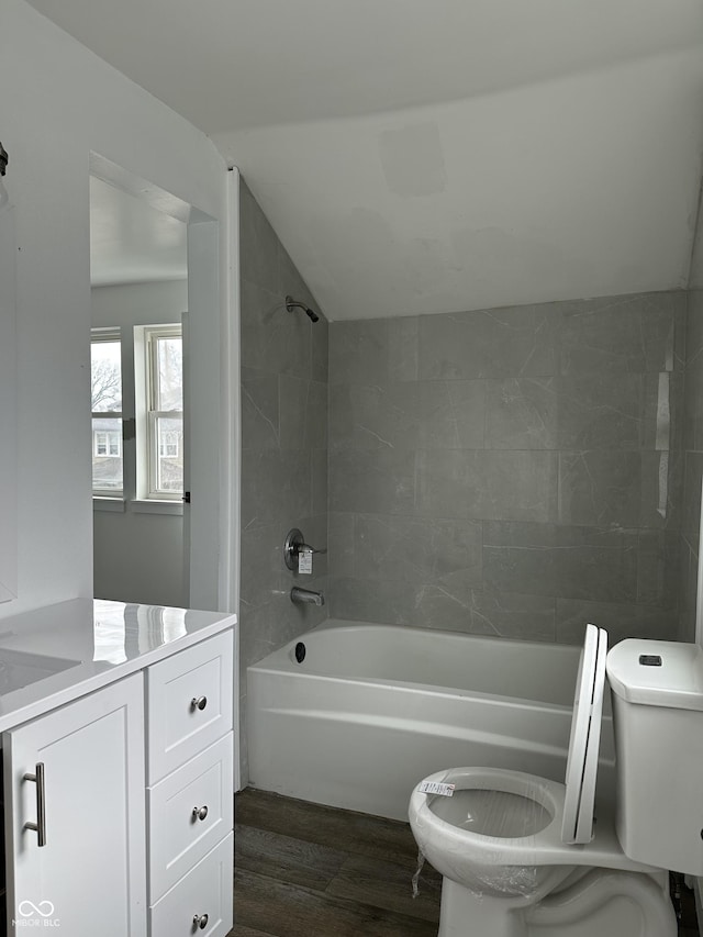 full bathroom featuring toilet, shower / bathing tub combination, vanity, vaulted ceiling, and wood finished floors