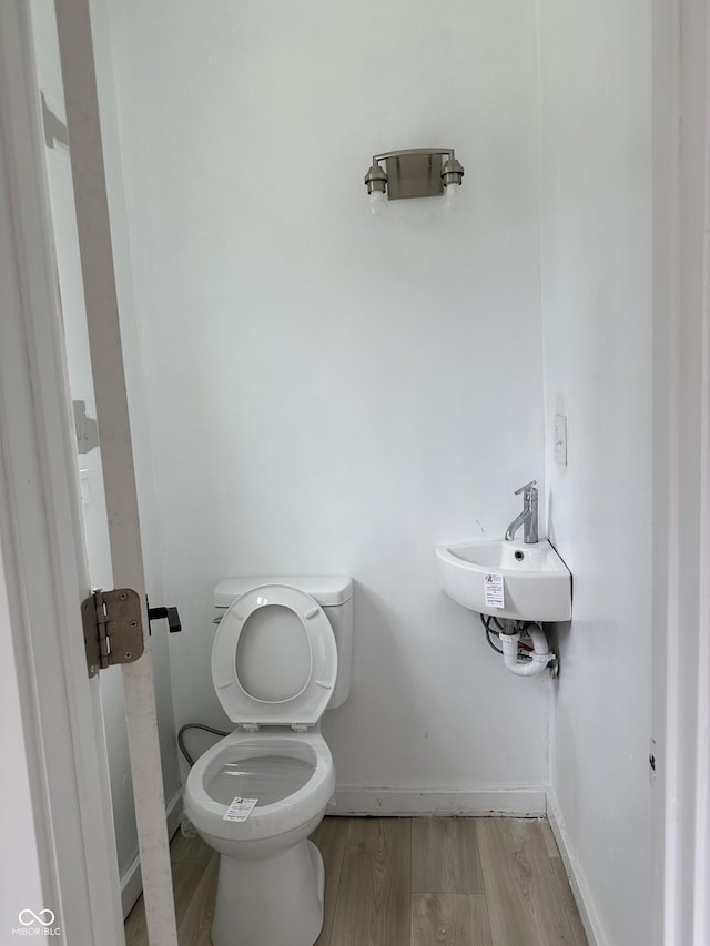 bathroom with toilet, wood finished floors, a sink, and baseboards