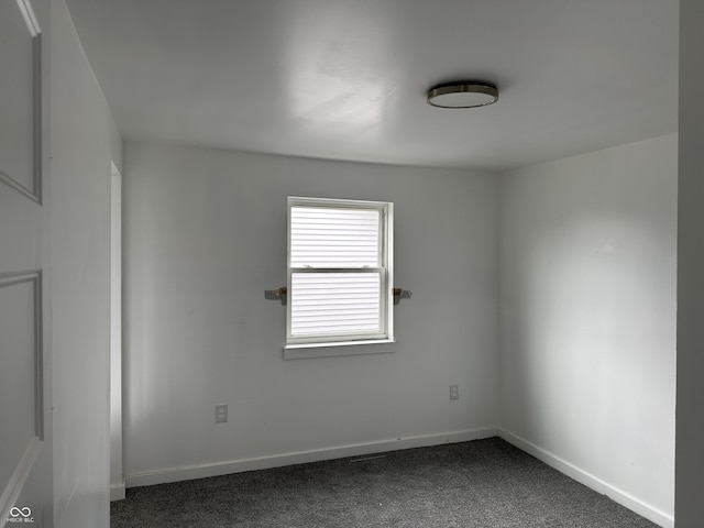 unfurnished room with dark carpet and baseboards