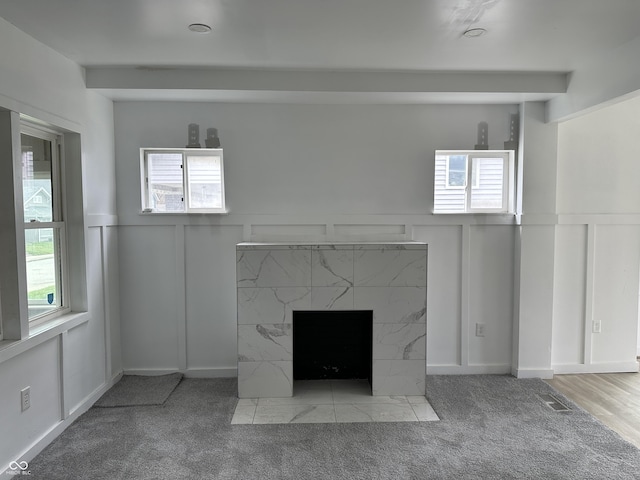 interior details with a decorative wall, a fireplace, wainscoting, and carpet floors