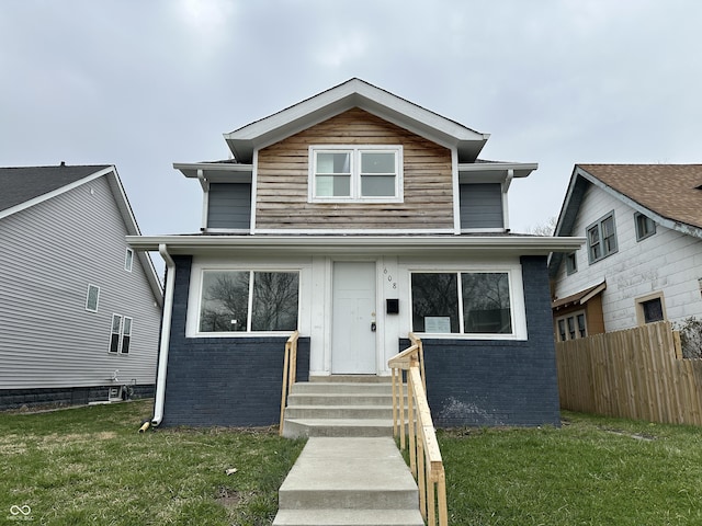 view of front facade featuring a front yard, brick siding, and fence