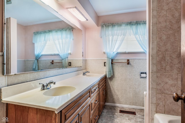 bathroom with a sink, visible vents, tile walls, and double vanity
