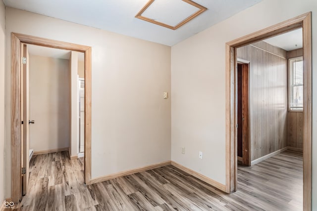 spare room featuring light wood-style flooring, baseboards, and attic access