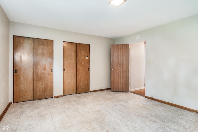 unfurnished bedroom with baseboards and multiple closets