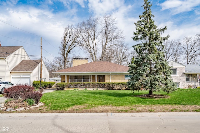 view of front facade with an attached garage, a chimney, and a front lawn