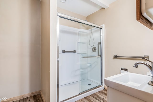 bathroom featuring a sink, a shower stall, and wood finished floors