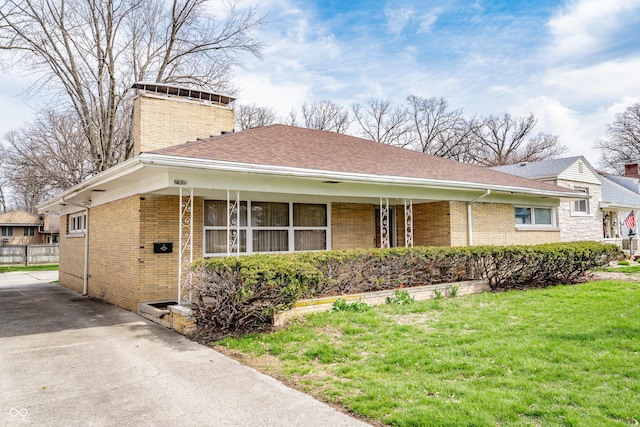 view of front of property featuring a chimney, a front yard, and brick siding