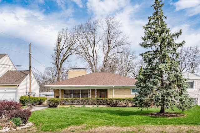 view of front of home with brick siding, roof with shingles, a front lawn, and a chimney