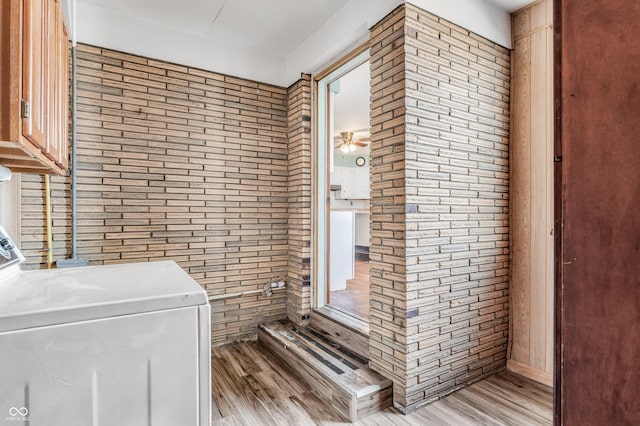 laundry room featuring ceiling fan, wood walls, washer / dryer, light wood finished floors, and cabinet space