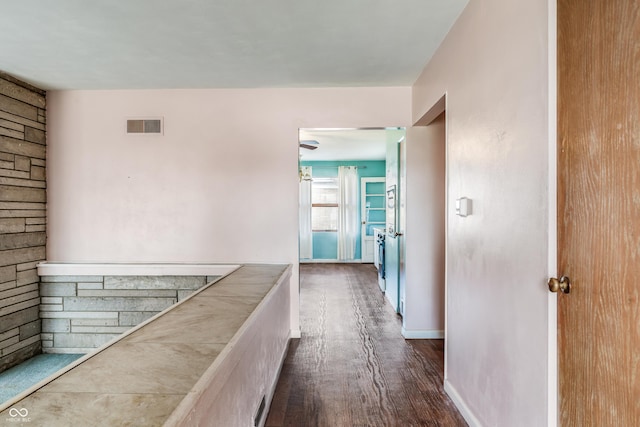 corridor with visible vents, baseboards, and dark wood finished floors