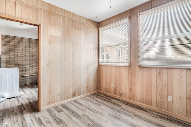 empty room with wooden walls, baseboards, and wood finished floors