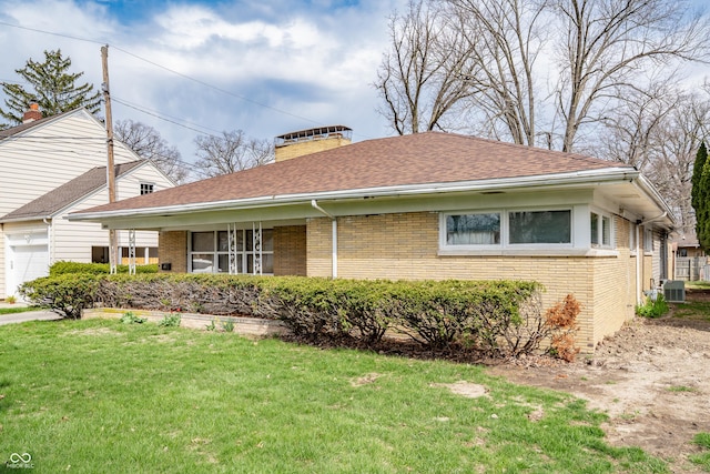 view of front facade featuring roof with shingles, a front lawn, brick siding, a chimney, and a garage