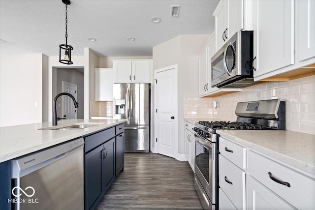 7012 Pickett Pl, Carmel, IN 46033 - kitchen featuring appliances with stainless steel finishes, a sink, white cabinetry, decorative light fixtures, and dark wood-style floors