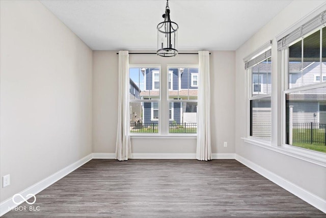 7012 Pickett Pl, Carmel, IN 46033 - unfurnished dining area with wood finished floors, baseboards, and a chandelier