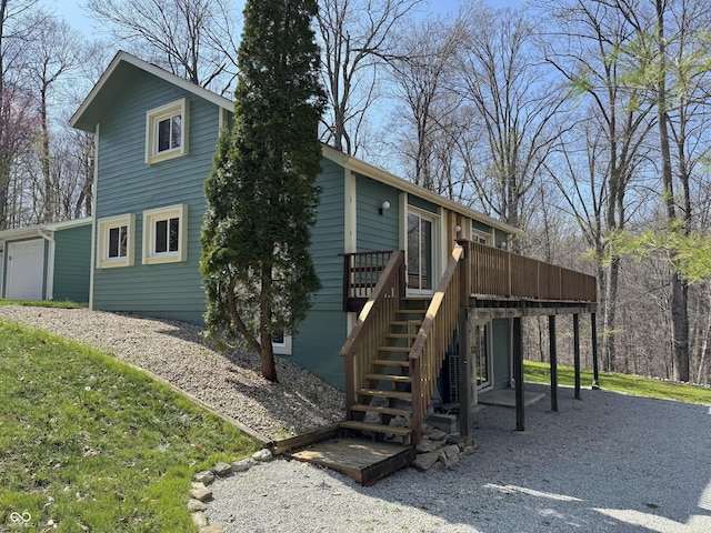 back of property with a garage, stairs, and a deck