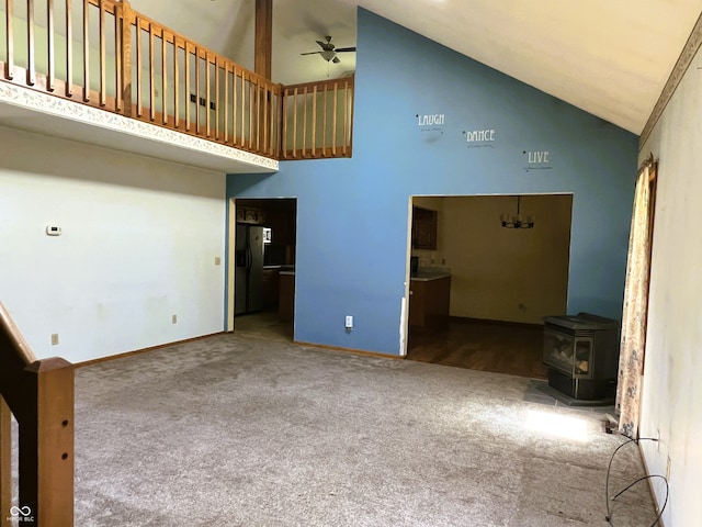 8809 Jonathon Pl, New Haven, IN 46774 - unfurnished living room with carpet floors, high vaulted ceiling, a ceiling fan, a wood stove, and baseboards