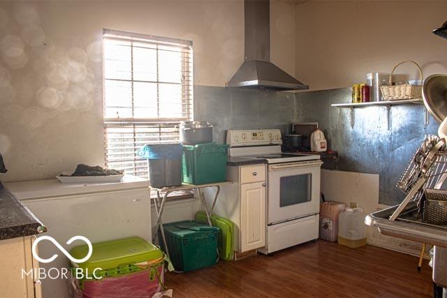 10105 Yosemite Ln, Indianapolis, IN 46234 - kitchen featuring dark wood-style flooring, white cabinetry, dark countertops, wall chimney exhaust hood, and electric stove