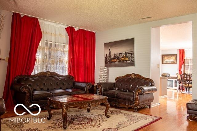 10105 Yosemite Ln, Indianapolis, IN 46234 - living area with a textured ceiling, wood finished floors, and visible vents