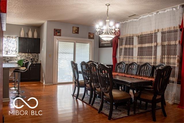 10105 Yosemite Ln, Indianapolis, IN 46234 - dining area with a chandelier, wood finished floors, and a textured ceiling