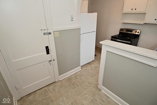 kitchen with baseboards, stainless steel electric range, light countertops, freestanding refrigerator, and white cabinetry