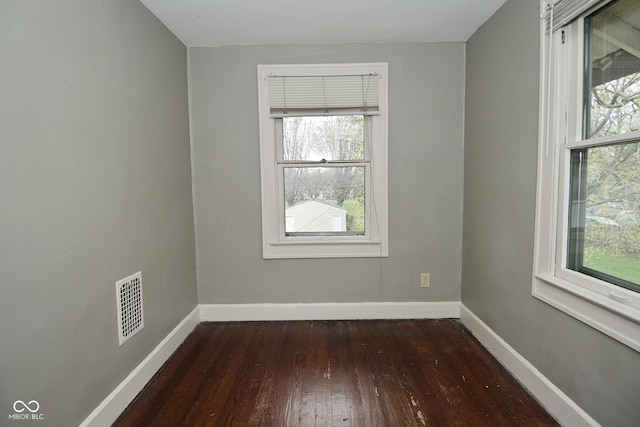 spare room featuring wood-type flooring, baseboards, and visible vents