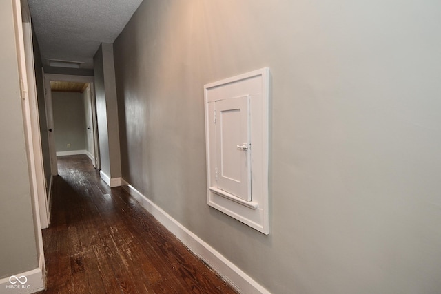 hall featuring baseboards, a textured ceiling, and dark wood finished floors