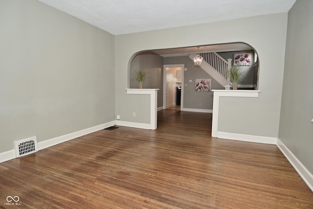unfurnished room featuring a chandelier, visible vents, baseboards, and wood finished floors