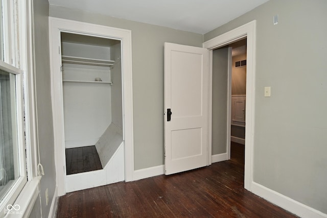 unfurnished bedroom with a closet, baseboards, and hardwood / wood-style flooring