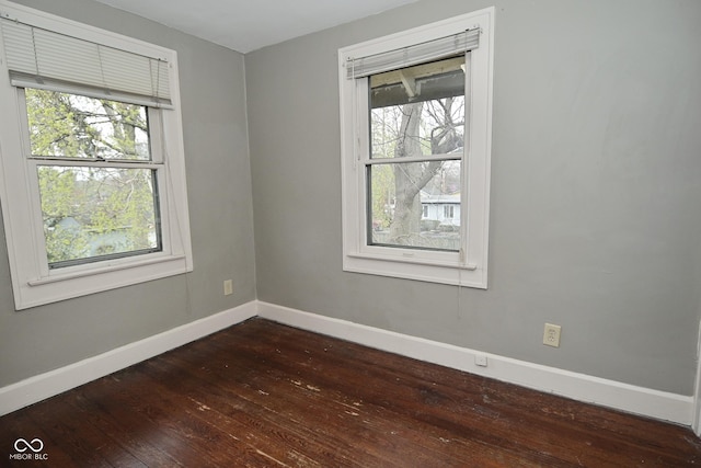 spare room with dark wood-style flooring, baseboards, and a healthy amount of sunlight