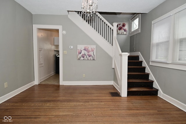 stairway with visible vents, baseboards, an inviting chandelier, and wood finished floors