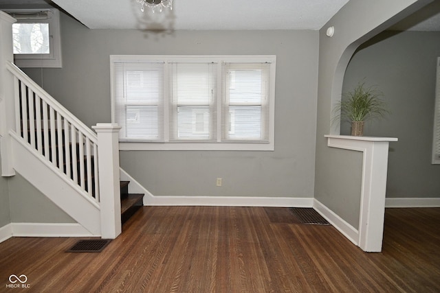 foyer entrance with visible vents, baseboards, wood finished floors, and stairs