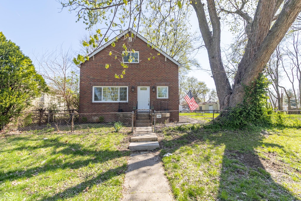view of front facade with a front yard, brick siding, and a fenced front yard