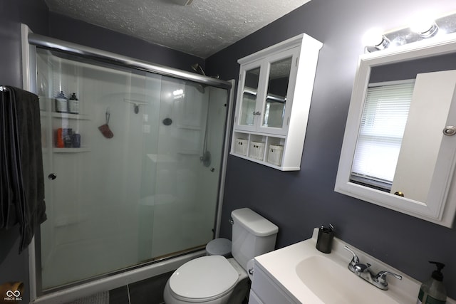 full bathroom with toilet, vanity, a textured ceiling, and a stall shower