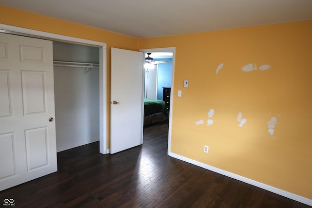 unfurnished bedroom featuring a closet, baseboards, and dark wood finished floors