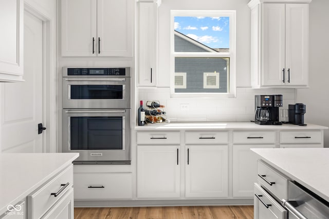 7210 Covington St, Lebanon, IN 46052 - kitchen featuring light countertops, white cabinets, decorative backsplash, light wood finished floors, and double oven