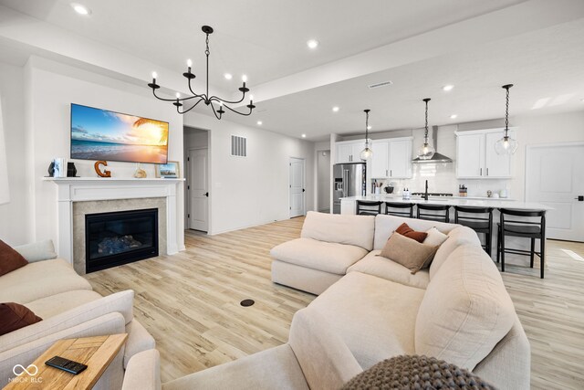 7210 Covington St, Lebanon, IN 46052 - living area with an inviting chandelier, a glass covered fireplace, visible vents, recessed lighting, and light wood finished floors
