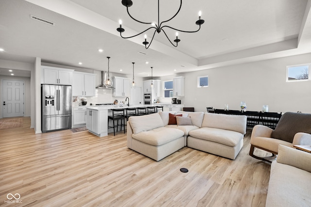 7210 Covington St, Lebanon, IN 46052 - living room with visible vents, a chandelier, a tray ceiling, recessed lighting, and light wood-style flooring