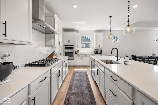 7210 Covington St, Lebanon, IN 46052 - kitchen with wall chimney exhaust hood, white cabinets, appliances with stainless steel finishes, a sink, and light wood finished floors