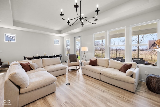 7210 Covington St, Lebanon, IN 46052 - living area featuring a tray ceiling, light wood-style floors, a healthy amount of sunlight, and a notable chandelier