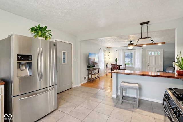 5945 Mcfarland Rd, Indianapolis, IN 46227 - kitchen featuring stainless steel fridge, a textured ceiling, butcher block counters, gas stove, and light tile patterned flooring