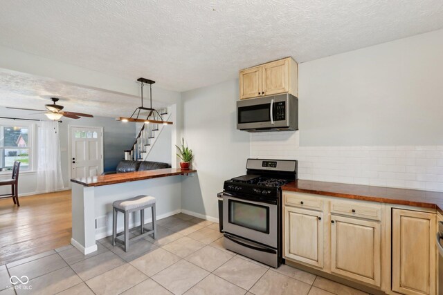 5945 Mcfarland Rd, Indianapolis, IN 46227 - kitchen with a textured ceiling, decorative backsplash, light brown cabinetry, and appliances with stainless steel finishes